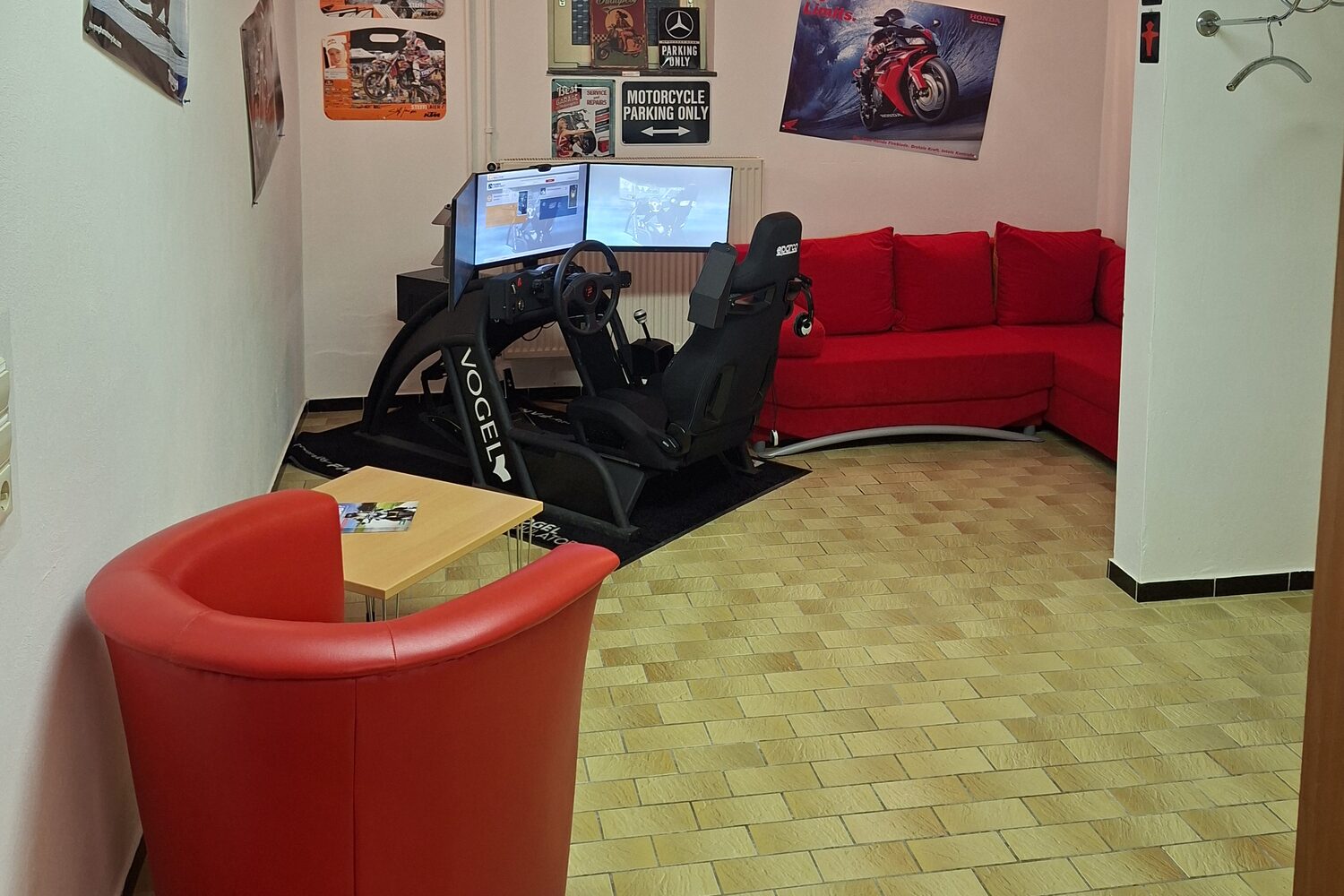 Simulator-Raum in Eppingen mit rotem Sessel, roter Couch und dem Fahrsimulator